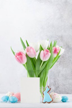 Lale çiçek, gingerbread çerezleri ve Paskalya yumurta Paskalya tebrik kartı. Selam yeri olan taş duvarın önünde