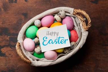 Sepet içinde renkli yumurtalı Paskalya tebrik kartı. Selam yeri olan ahşap masa üzerinde Üstten Görünüm