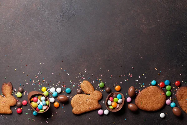 カラフルなジンジャーブレッド クッキー チョコレートの卵のお菓子とイースターのグリーティング カードの背景 あなたの挨拶のためのスペースと石のテーブルのトップ ビュー — ストック写真