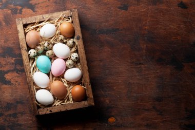 Ahşap masa kutusunda tavuk ve bıldırcın yumurtası. Paskalya tebrik kartı. Üstten Görünüm 