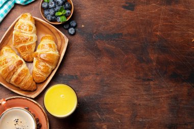 Kruvasan ve ahşap masa üzerinde çilek ile portakal suyu bir bardak kahve fincanı. Kahvaltı konsepti 