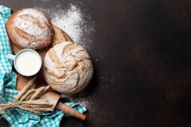 Ev yapımı ekmek ve fincan süt ahşap kesme tahtası üzerinde ve oklava taş masada. Üstten Görünüm 