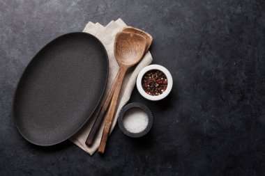 Ahşap mutfak eşyaları, boş levha ve taş zemin üzerine baharat pişirme