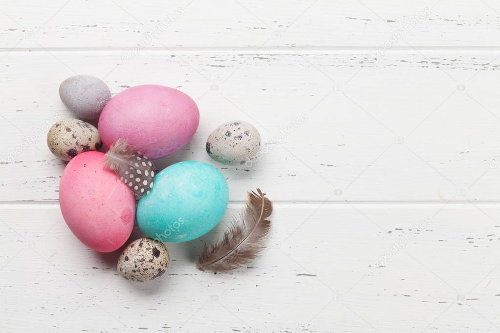 Easter greeting card with colorful eggs and little quail eggs on wooden white background