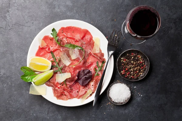 霜降り牛肉のカルパッチョとルッコラ レモン パルメザン チーズと赤ワインのガラス — ストック写真