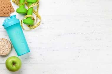 Halter, yeşil elma ve içki şişesi üzerinde ahşap masa