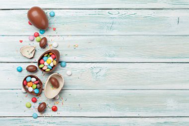 Çikolata yumurta ve ahşap arka plan üzerinde renkli şekerler ile Paskalya tebrik kartı