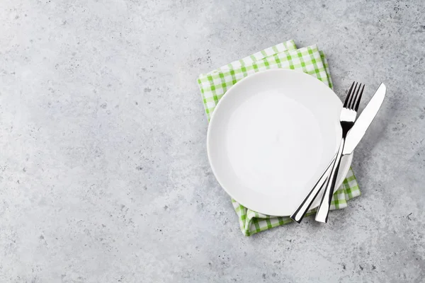 Empty plate, knife, fork and napkin on stone background