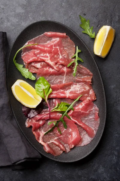 Carpaccio Manzo Marmorizzato Con Foglie Verdi Rucola Limone Fondo Pietra — Foto Stock