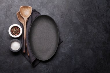 Ahşap mutfak aletleri ve siyah taş zemin üzerine boş levha