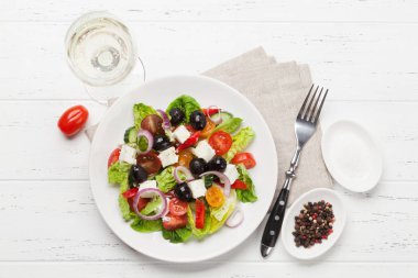 Yunan salata salatalık, domates, biber, marul, soğan, beyaz peynir ve zeytin ile zeytinyağı ahşap tablo ile giyinmiş 