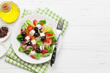 Yunan salata salatalık, domates, biber, marul, soğan, beyaz peynir ve zeytin ile zeytinyağı ahşap tablo ile giyinmiş 