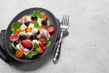 Yunan salata salatalık, domates, biber, marul, soğan, beyaz peynir ve zeytin ile zeytinyağı taş zemin üzerine ile giyinmiş