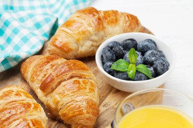 Kahve, kruvasan, portakal suyu ve çilek Beyaz ahşap zemin üzerinde