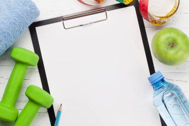 Ahşap arka planda Not defteri ile yeşil dumbbells, su şişesi ve elma