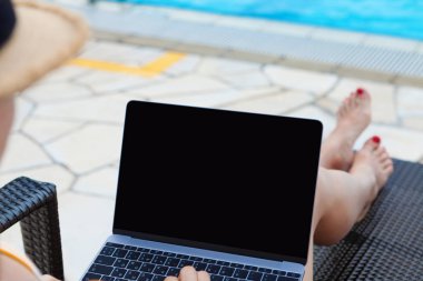 Yüzme Havuzu yakındaki iş için dizüstü bilgisayar kullanan genç kadın