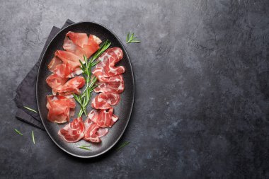 Geleneksel İspanyol Jamon, Prosciutto Crudo, İtalyan Parma jambon taş arka planda biberiye ile hizmet 