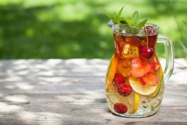 Bahar bahçesinde ahşap masada yaz meyve ve çilek ile ev yapımı Sangria 