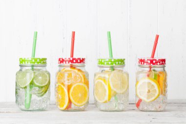 Beyaz ahşap arka planda cam kavanozlarda Taze narenciye limonata