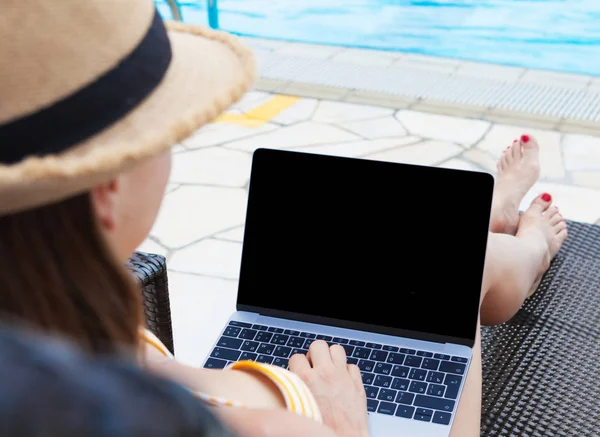 Yüzme Havuzu yakındaki iş için dizüstü bilgisayar kullanan genç kadın