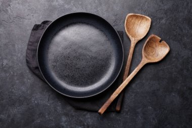 Ahşap mutfak aletleri ve karanlık taş zemin üzerine boş levha 