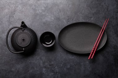 Boş levha, kupa, çaydanlık ve çubuk siyah dokulu tablo üzerinde