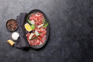 Arugula, limon ve parmesan peyniri ile mermer Beef Carpaccio 'nun üst görünümü