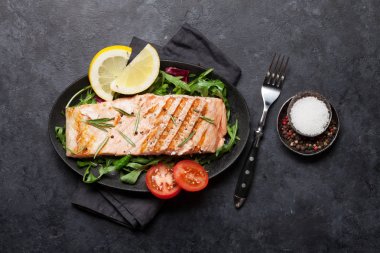 Salata yaprakları üzerinde tuz, biber ve biberiye ile ızgara somon balık fileto