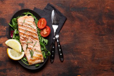 Salata yaprakları üzerinde tuz, biber ve biberiye ile ızgara somon balık fileto