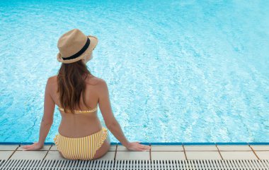 Yüzme havuzunda dinlenen genç bir kadın.