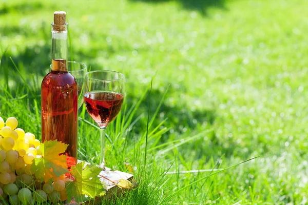Botella de vino rosa y uvas — Foto de Stock