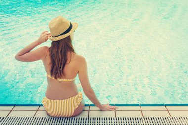 Yüzme havuzunda dinlenen genç bir kadın.