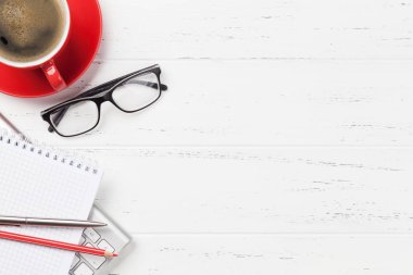 Not defteri, kahve fincanı ve sarf malzemeleri içeren ofis masası