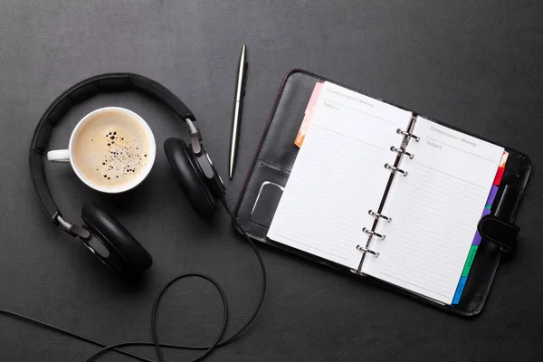 Irodai íróasztal jegyzetfüzetbe, kávéscsésze és fejhallgató — Stock Fotó