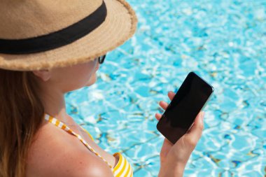 Bir yüzme havuzu yakın Smartphone kullanarak genç kadın