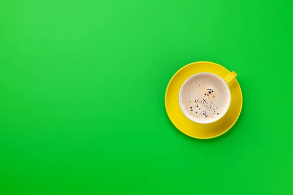 緑の背景に黄色のコーヒーカップ — ストック写真