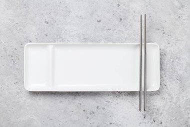 Taş masa üzerinde boş tabak ve çubuklar