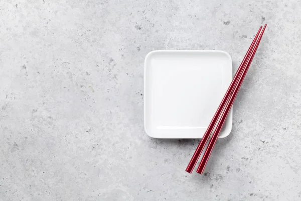 Empty plate and chopsticks over stone table — Stock Photo, Image