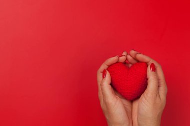 Kırmızı kalp oyuncak tutan kadın elleri