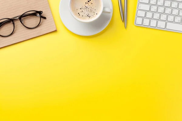 Office gele achtergrond met koffie, benodigdheden en computer — Stockfoto