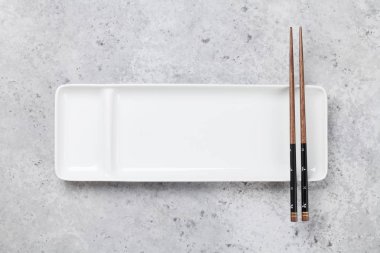 Taş masa üzerinde boş tabak ve çubuklar