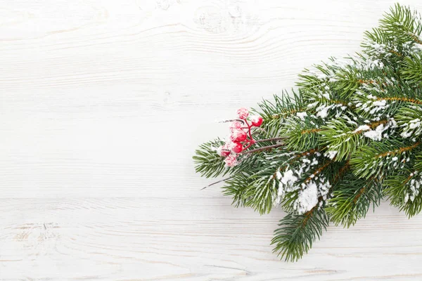 Kerst dennenboom tak bedekt met sneeuw op hout — Stockfoto