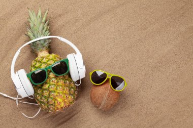 Olgun ananas ve hindistan cevizi ve güneş gözlüğü ile kumun üzerinde fotokopi alanı. Seyahat ve tatil konsepti. Üst görünüm düzlüğü