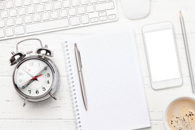 Ofis masasında akıllı telefon, malzeme, kahve ve çalar saat var. Sabah ya da teslim tarihi konsepti. Metnin için en üstte boşluk var. Düz yatıyordu