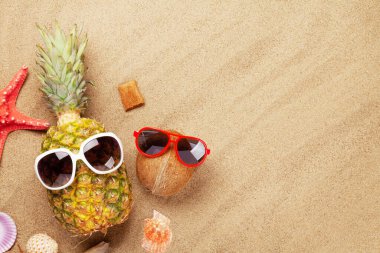 Olgun ananas ve hindistan cevizi ve güneş gözlüğü ile kumun üzerinde fotokopi alanı. Seyahat ve tatil konsepti. Üst görünüm düzlüğü