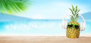 Parlak dalgalı tropikal deniz, güneş gözlüklü ananas ve sıcak kumsalda kulaklık. Kopya alanı ile seyahat ve tatil kavramı