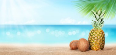 Yaz tropikal denizi, köpüklü dalgalar, ananas ve hindistan cevizleri sıcak kumsalda. Kopya alanı ile seyahat ve tatil kavramı