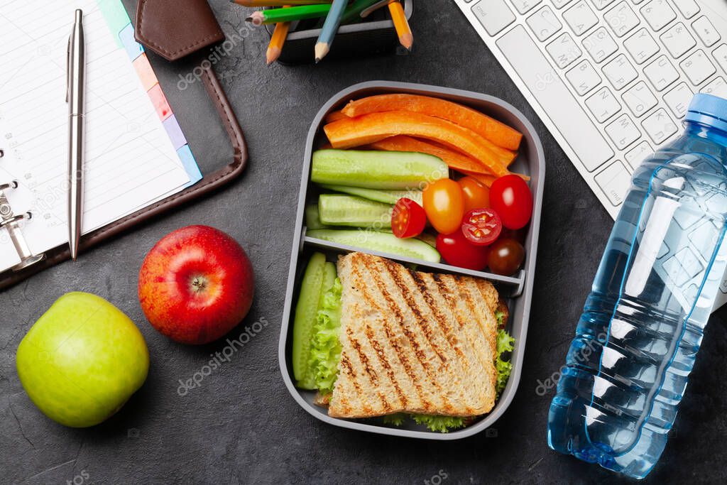 Healthy lunch box with sandwich and vegetables on office table. Top view. Flat lay