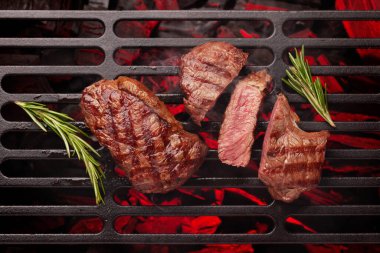 Beef steaks cooking on grill with spices and herbs. Top view flat lay clipart