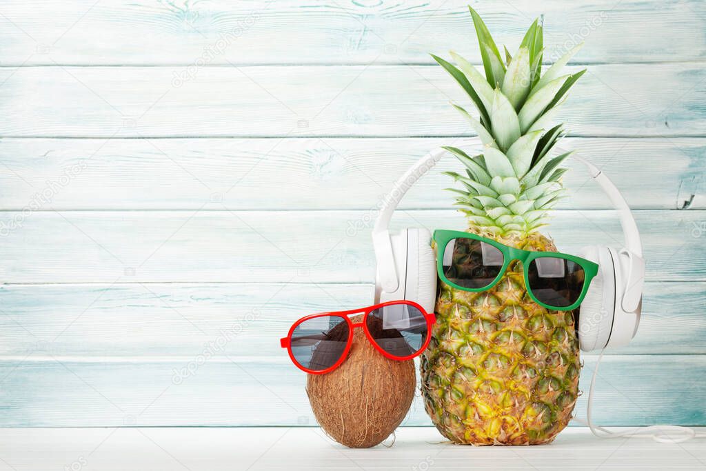 Ripe pineapple and coconut with sunglasses and headphones. Travel and vacation concept. With copy space